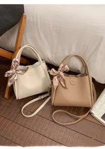 Detail der Leder-Eimertasche mit Lychee-Muster und Seidentuchgriff auf Holzboden