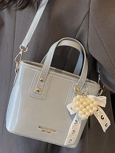 Minimalist light gray patent leather bucket bag with golden hardware and pearl heart charm