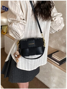 Detail of black woven crossbody bag with gold chain strap and plush monster charm