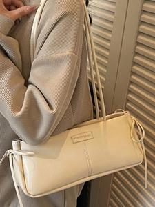 Minimalist cream rectangular underarm bag with ribbon bow detail and fashion label