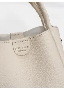 Detailaufnahme der cremefarbenen Lederstruktur mit Lychee-Maserung und geprägtem Logo