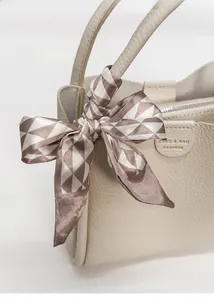 Detail der beigen Lederhandtasche mit Seidenschal-Schleife und Logoprägung