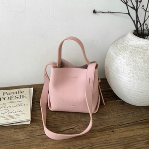 Detailed close-up of light pink lychee grain leather bucket bag on a wooden table