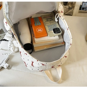 Top view of spacious main compartment in white floral backpack with books and items