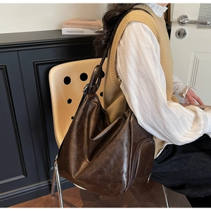 Detail view of large dark brown tote bag showing side zipper pocket and supple leather texture