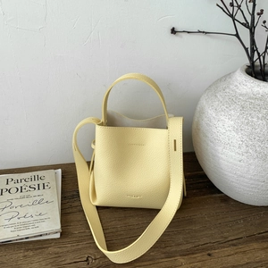 Detailed macro view of yellow lychee grain leather bucket bag on rustic wooden table