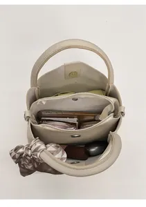 Draufsicht der beigen Beuteltasche mit drei Fächern und dekorativem Seidenschal-Detail
