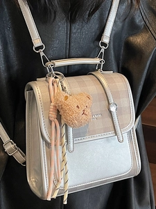 Vintage silver-grey leather backpack for women featuring a flap cover and cute teddy bear charm