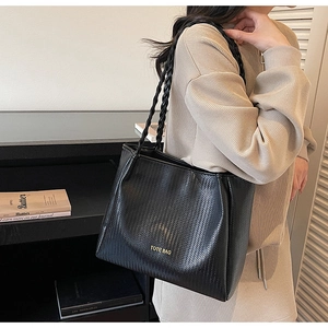 Détail de la texture tressée et des doubles anses sur un grand sac cabas noir chic