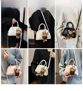 Drei Farben schicker Bowlingtaschen mit Bärenanhänger, getragen von einem Model