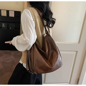 Detail of dark brown tote bag with vintage oil wax leather texture and slouchy design