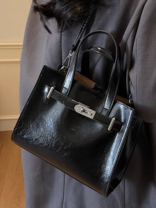 Elegant black wrinkled patent leather crossbody bag with silver clasp and top handle