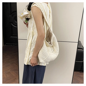 Close-up of a large beige crochet shoulder bag showing intricate woven floral patterns