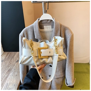 Detail of white pleated shoulder bag featuring a chunky gold chain and large square buckle