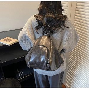Detailed back view of a dark grey triangle backpack featuring a sleek faux leather texture