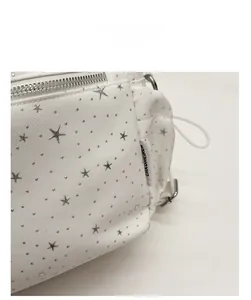 Detailed close-up of white fabric bag with silver star-shaped metal rivets and texture