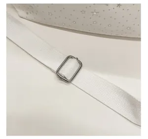 Detail of adjustable wide fabric strap with silver metal buckle on white star bag