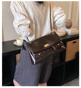 Detail of dark brown quilted leather shoulder bag with golden chain and metal lock