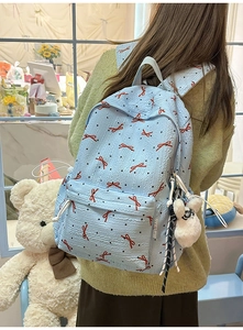 Detail of light blue seersucker backpack with red bows and plush bunny pendant accessory