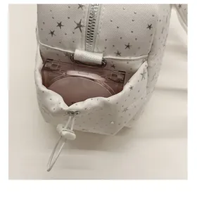 Detail view of side drawstring pocket on white star pattern shoulder bag with a makeup compact