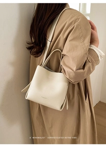 Detailed macro view of the cream bucket bag showing high-quality lychee grain leather texture