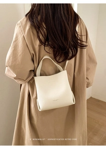 Close-up of beige lychee grain leather bucket bag with brand logo and crossbody strap
