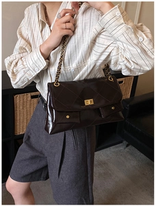 Detail of dark brown quilted leather tote with gold metal chain strap and turn-lock