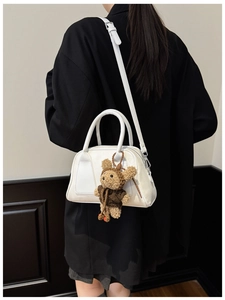 Weiße Leder-Tragetasche im Detail mit süßem Teddybär-Anhänger und verstellbarem Gurt