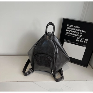 Detail of black geometric triangle backpack in glossy PU leather with front zipper pocket