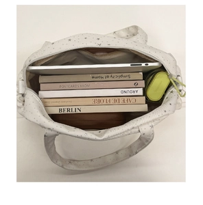Spacious interior of white star patterned tote bag holding a tablet, books, and umbrella