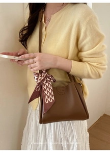 Nahaufnahme der braunen Leder-Eimertasche mit dekorativem Seidenschal am Taschengriff
