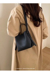 Detailed view of black pebbled leather bucket bag on model for elegant styling