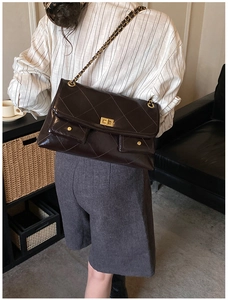 Detail of quilted dark coffee shoulder bag with gold chain strap and dual front pockets