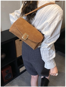 Sac bandoulière en cuir dépoli marron avec boucle dorée porté par un mannequin