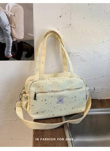 Detailed view of yellow star pattern crossbody bag with silver prints and purple logo