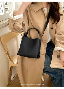 Detail shot of a black leather bucket bag being styled in a chic vintage interior