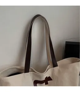 Détail du grand sac cabas en toile avec bandoulières en cuir brun et imprimé lettre f