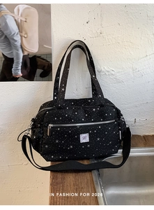 Detail view of black canvas star pattern bag with silver zipper and front brand label