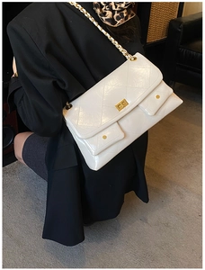 Detail of quilted tote bag featuring golden twist lock and chain strap on female model