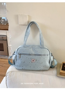 Detail of light blue star print handbag with bow patch and silver patterns on a white sofa