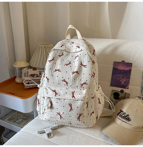 Detail of the white backpack featuring a red bow pattern and textured crinkle fabric