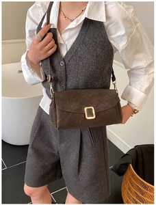 Gros plan sur un sac carré en cuir marron avec boucle en métal doré pour femme