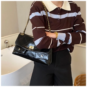 Close-up of quilted black leather tote bag with gold chain strap and dual front pockets