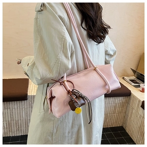 Detail showing light pink Boston bag with colorful charms and silk scarf decoration