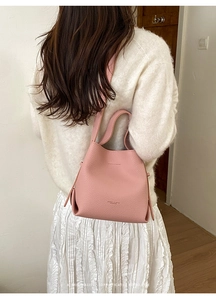 Detailed view of pink pebble leather bucket bag with top handle and shoulder strap