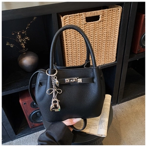 Detail of black lychee grain leather bucket bag featuring silver lock and bow charm
