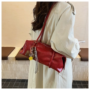 Close-up of red pleated texture handbag with yellow smiley charm and silver zipper detail