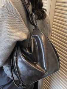 Chic dark gray pleated tote bag in soft PU leather shown on shoulder with spacious design
