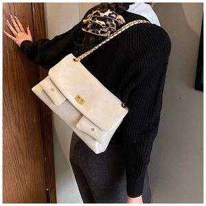 Detail of a beige quilted leather chain bag with gold metal square lock and twin front pockets