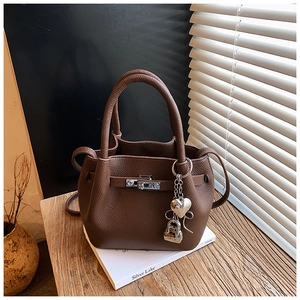 Close-up of coffee brown lychee leather bucket bag with silver heart lock detail